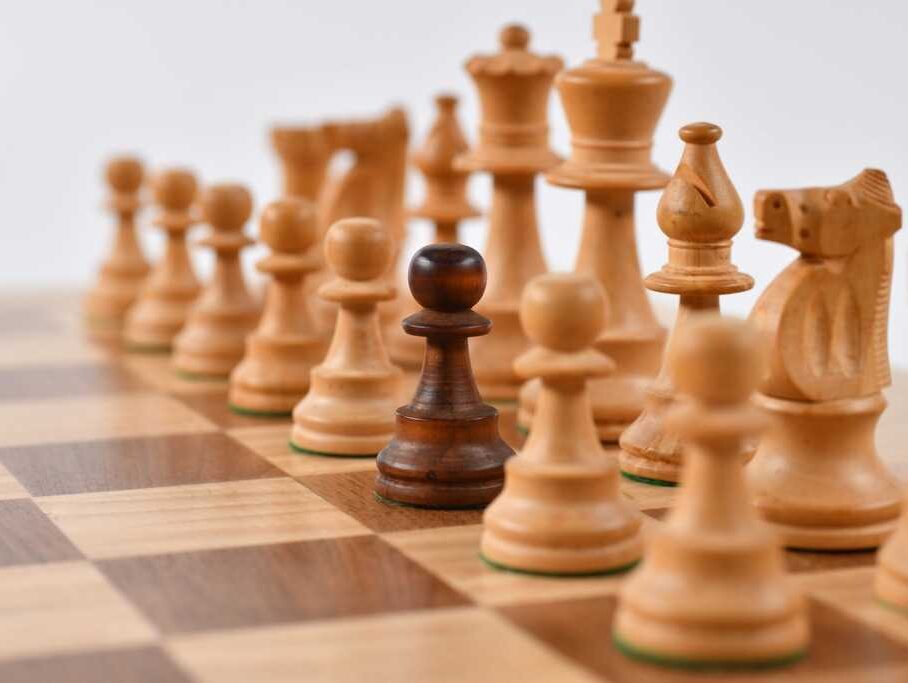 Czarny pion wśród białych na szachownicy